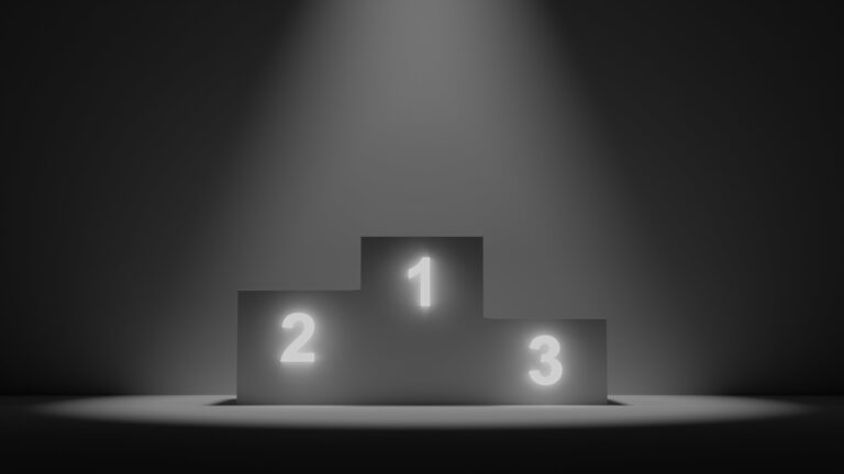 A grey podium with spotlight on it. first second and third highlighted numbers on the 3 levels of the podium.
