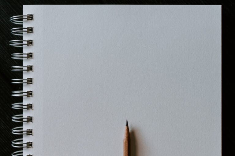 A blank white page n a ring bound notebook with a pencil on top